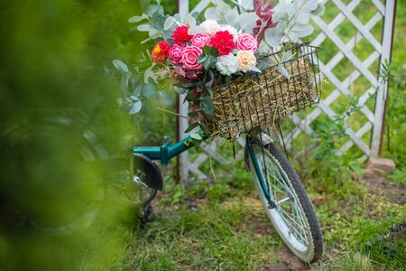 Beautiful bicycle with flowers in a basket stands on an avenue in a park at sunsetの写真素材