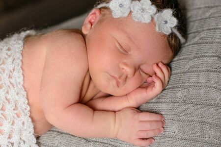 A little newborn girl eight days old in a beautiful outfit sleeps cute