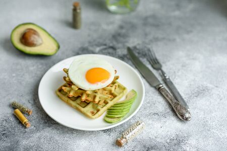 Fresh delicious and nutritious breakfast with waffles with spinach, fried egg and avocado piecesの写真素材
