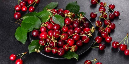 Close up of pile of ripe cherries with stalks and leaves. Large collection of fresh red cherries. Ripe cherries backgroundの写真素材