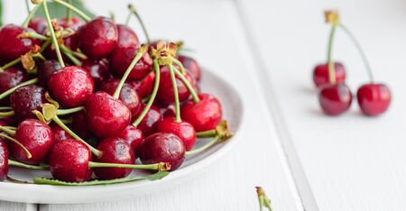 Close up of pile of ripe cherries with stalks and leaves. Large collection of fresh red cherries. Ripe cherries backgroundの写真素材