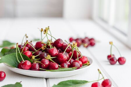 Close up of pile of ripe cherries with stalks and leaves. Large collection of fresh red cherries. Ripe cherries backgroundの写真素材