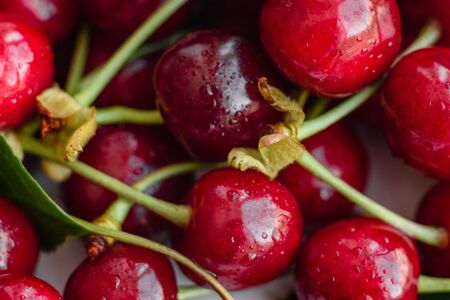 Close up of pile of ripe cherries with stalks and leaves. Large collection of fresh red cherries. Ripe cherries backgroundの写真素材