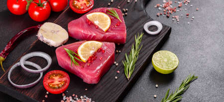 Fresh tuna fillet steaks with spices and herbs on a black background. Preparing tuna for bakingの写真素材