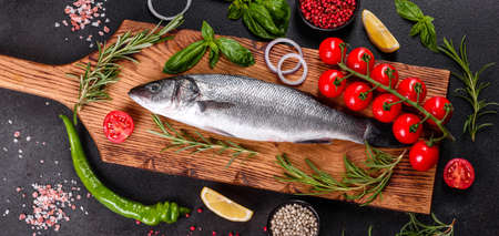 Fresh fish seabass and ingredients for cooking. Raw fish seabass with spices and herbs on a dark...