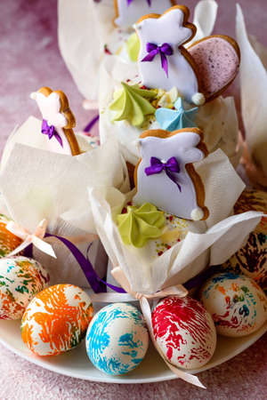 Easter bright multicolored eggs with Easter pies on a white ceramic plate on a pink concrete...