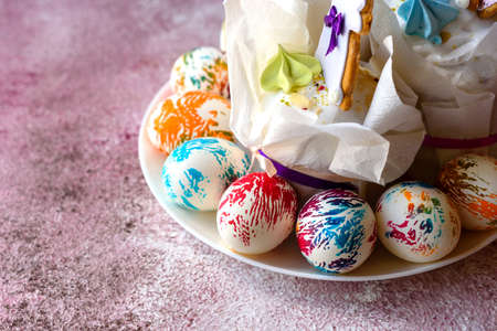 Easter bright multicolored eggs with Easter pies on a white ceramic plate on a pink concrete...