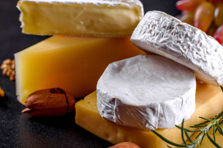 Beautiful delicious camembert cheese, parmesan, brie with grapes and figs on a wooden board. Snacks for wine on holidayの写真素材