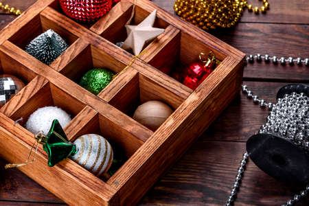 Christmas toys and decorations in a beautiful wooden box on a wooden table. Christmas tree decoration, preparation for the holidayの写真素材