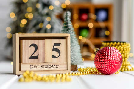 Beautiful multi-colored Christmas decorations on a light wooden table with garlands and Christmas trees in the background. Preparing for the holidayの写真素材