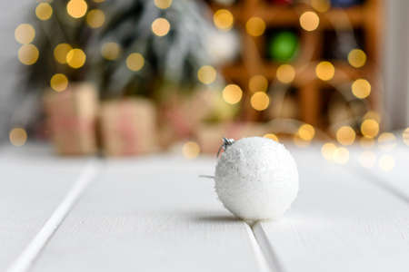 Beautiful multi-colored Christmas decorations on a light wooden table with garlands and Christmas trees in the background. Preparing for the holidayの写真素材