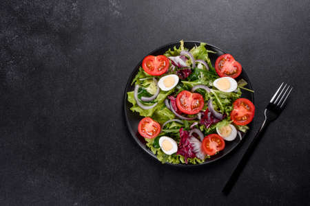Fresh delicious vegitarian salad of chopped vegetables on a plate on a dark concrete backgroundの写真素材