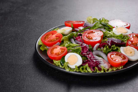Fresh delicious vegitarian salad of chopped vegetables on a plate on a dark concrete backgroundの写真素材