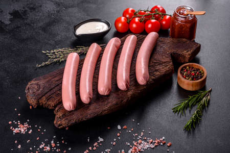 Delicious fresh boiled sausages with vegetables and spices on a dark concrete backgroundの写真素材