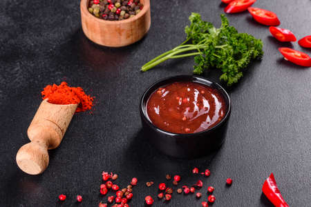 Spicy seasoning of Georgian cuisine adjika in a bowl with red pepper and garlic on a concrete table close-upの写真素材