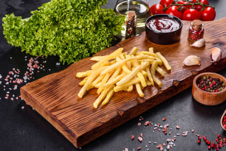 Fresh hot french fries with salt vegetables and spices on a dark concrete backgroundの写真素材