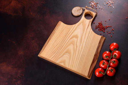 Cutting board with salt, spices and herbs on a dark concrete background. Cooking Healthy Food