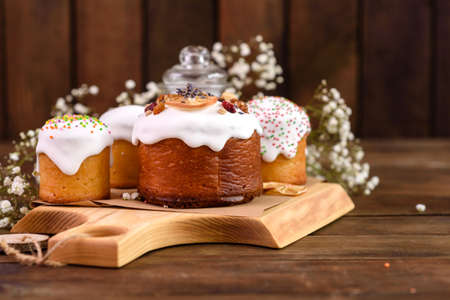 Festive cakes with white glaze, nuts and raisins with Easter eggs on the festive table. Preparations for Easterの写真素材