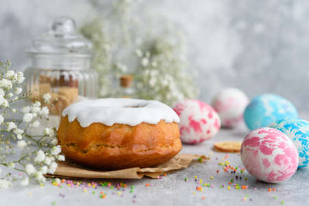 Festive cakes with white glaze, nuts and raisins with Easter eggs on the festive table. Preparations...