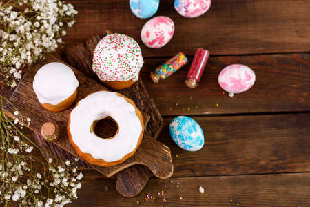 Festive cakes with white glaze, nuts and raisins with Easter eggs on the festive table. Preparations...