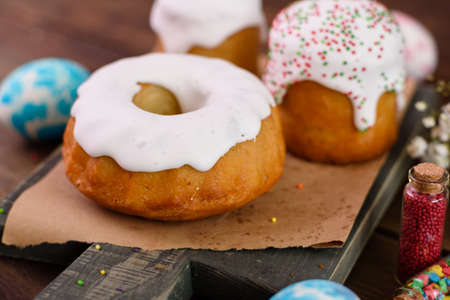 Festive cakes with white glaze, nuts and raisins with Easter eggs on the festive table. Preparations...