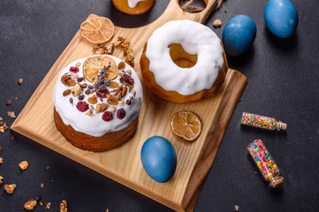 Festive cakes with white glaze, nuts and raisins with Easter eggs on the festive table. Preparations...