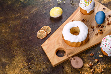 Festive cakes with white glaze, nuts and raisins with Easter eggs on the festive table. Preparations...