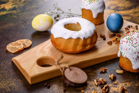 Festive cakes with white glaze, nuts and raisins with Easter eggs on the festive table. Preparations...