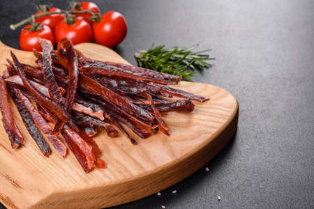 Tasty hearty meat salted and dried with pieces of spices and herbs. Fast and hearty snackの写真素材
