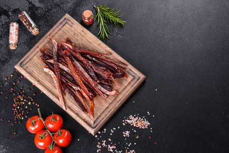 Tasty hearty meat salted and dried with pieces of spices and herbs. Fast and hearty snackの写真素材