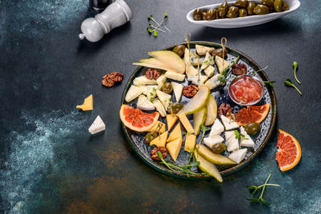 Cutting four types of cheese: goats, parmesan, camembert and brie with pear and dried grapefruit slices and microgreens. Tasty healthy snackの写真素材