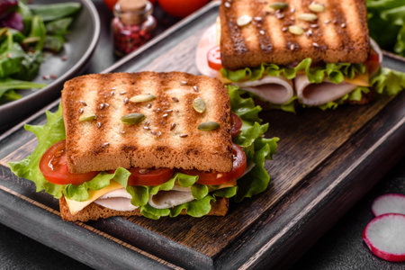 Delicious sandwich with crisp toast, ham, lettuce and tomatoes. Quick nourishing breakfastの写真素材