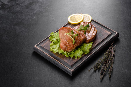 Delicious juicy tuna steak grilled with spices and herbs and lemon slices on a dark backgroundの写真素材