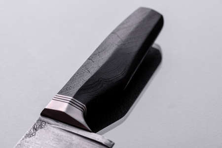 A large handmade hunting knife lying on a dark monotone background