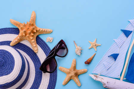 Beach accessories: glasses and hat with shells and sea stars on a colored background. Summer backgroundの写真素材