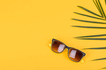 Beach accessories: glasses and hat with shells and sea stars on a colored background. Summer...