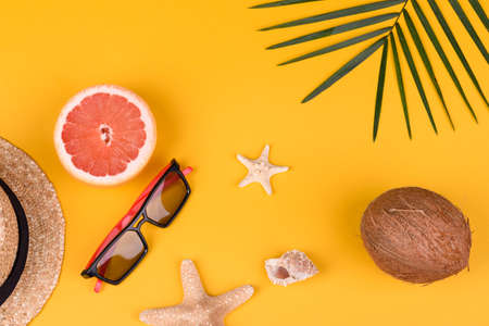 Beach accessories: glasses and hat with shells and sea stars on a colored background. Summer...