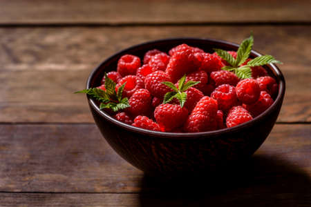 Delicious fresh juicy red raspberries on a dark table. Seasonal berries and fruits