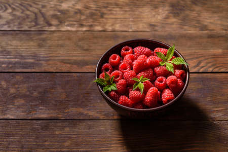 Delicious fresh juicy red raspberries on a dark table. Seasonal berries and fruits