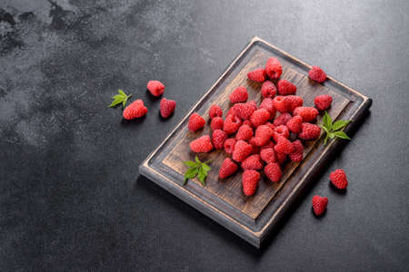 Delicious fresh juicy red raspberries on a dark table. Seasonal berries and fruits