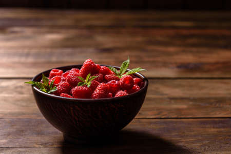 Delicious fresh juicy red raspberries on a dark table. Seasonal berries and fruitsの写真素材