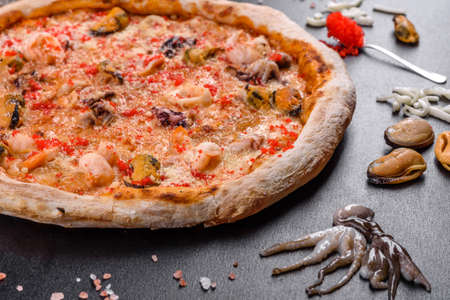 Tasty sliced pizza with seafood and tomato on black background. Mediterranean cuisineの写真素材
