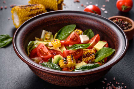 Delicious fresh salad with tomatoes, avocado, cheese and grilled corn with olive oil. Mediterranean...