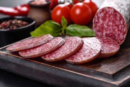 Spanish dried sausage salami on a dark concrete background. Preparation of delicious fresh sandwichesの写真素材
