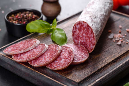 Spanish dried sausage salami on a dark concrete background. Preparation of delicious fresh...