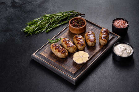 Grilled sausage with the addition of herbs and vegetables on the dark background. Grilling food, barbecueの写真素材