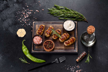 Grilled sausage with the addition of herbs and vegetables on the dark background. Grilling food, barbecueの写真素材