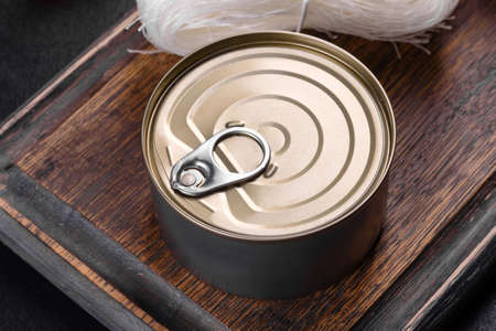 Canned tuna fillet meat in olive oil, on black background, flat lay
