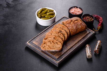 Delicious fresh black bread sliced with slices on a dark concrete background. Preparation of...