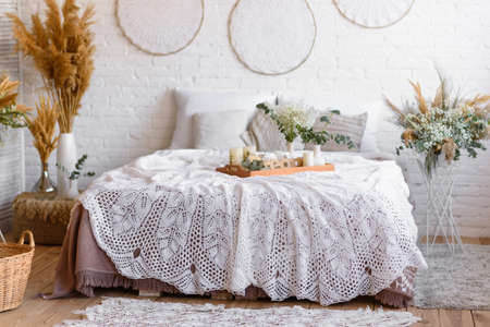 Beautiful home interior with white and beige tones, with dream catchers, dry flowers and a bed. Interior of a cozy houseの写真素材